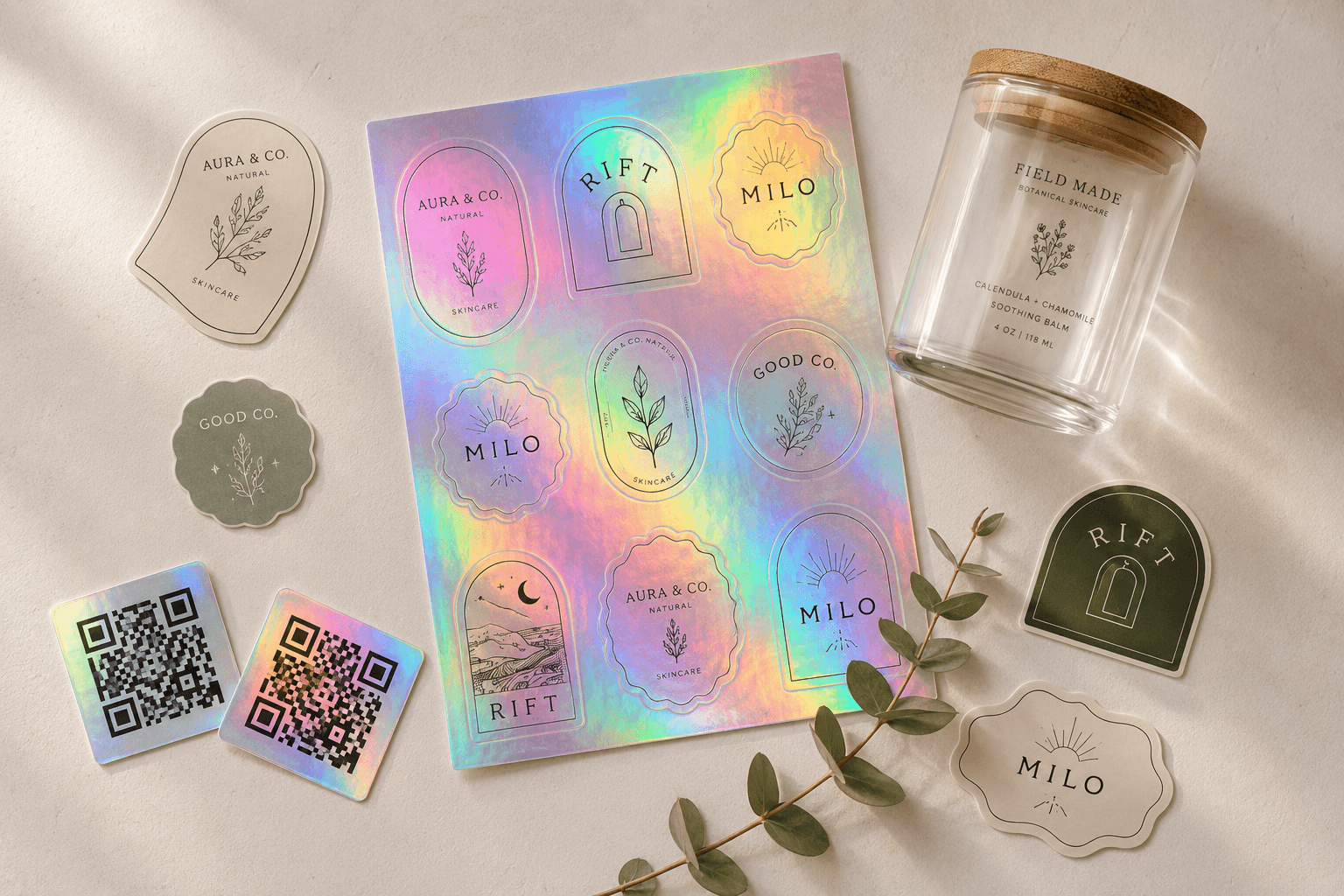 Specialty printed products: holographic sticker sheet with rainbow shimmer, holographic QR code stickers, clear front-adhesive label on a Field Made glass jar, and unique die-cut shapes